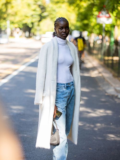 Streetstyle mit einem weißen Rollkragenpullover, einer stone-washed Jeans und einem weißen Blazermantel.