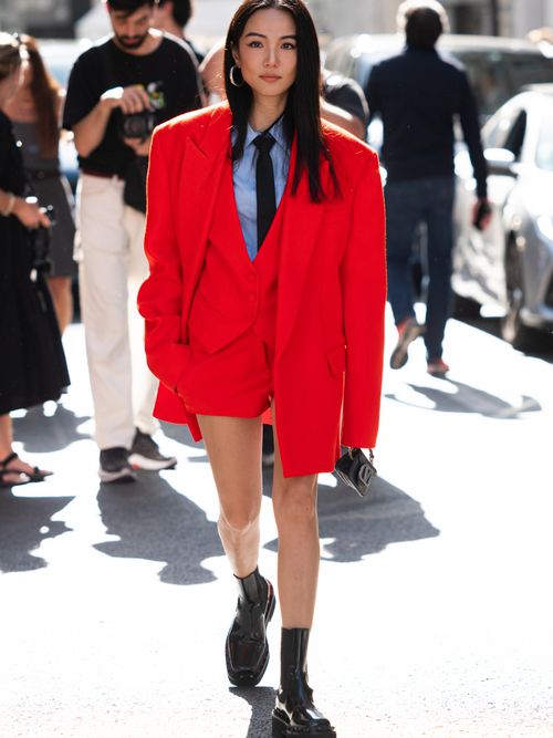 Yoyo Cao trägt eine rote Hosenanzug-Kombi mit Hemd und Krawatte auf der Paris Fashion Week.