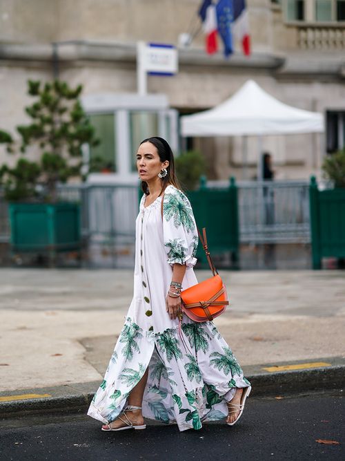 Ein Streetstyle Look mit einem weißen Kleid mit Palmenprint und einer orangefarbenen Loewe Bag.