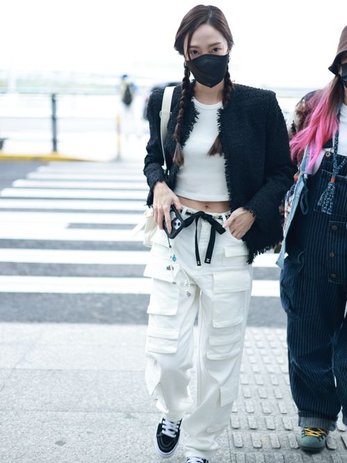 Jessica Jung arrives in Shanghai wearing a black tweed blazer, a white cropped tank top, baggy white cargo pants with a black bow belt, a white shoulder bag, and black Vans Old Skool sneakers.