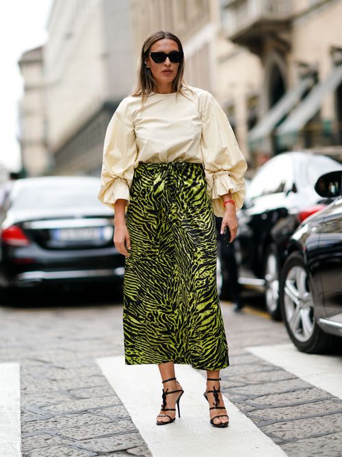 Ein Gast trägt eine Bluse mit Puffärmeln und einen grünen Leo-Rock mit High Heels auf der Milan Fashion Week.