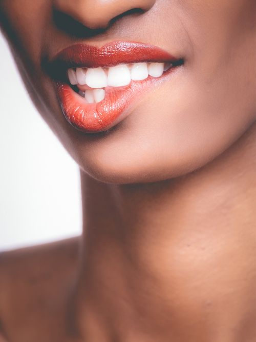 Gesichtsausschnitt einer Frau mit rotem Lippenstift, die sich auf die Lippen beißt.