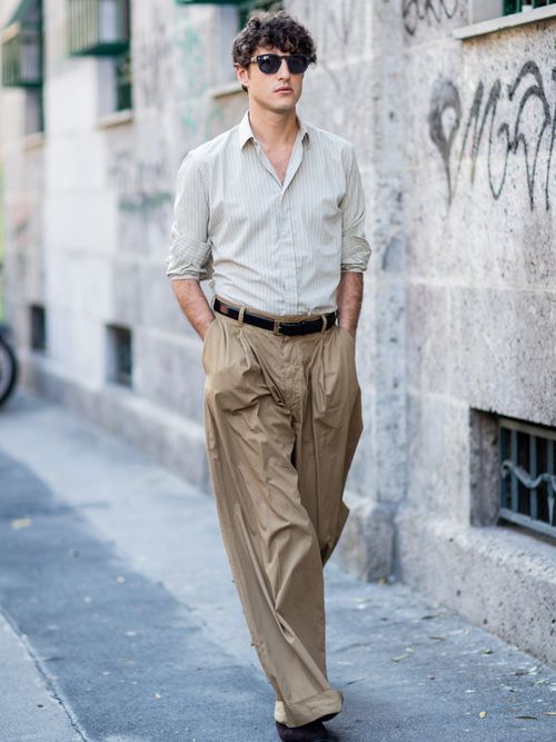 Street Style Look von der Milan Fashion Week, wo ein Gast ein gestreiftes Hemd mit hochgeschnittenen weiten Hose und Gürtel trägt.