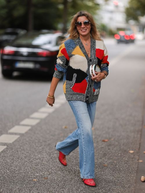 Yasmin von Schlieffen-Nannen trägt einen Mulitcolor Knit Cardigan zu einer ausgestellten Jeans mit roten Schuhen und Sonnenbrille in Hamburg