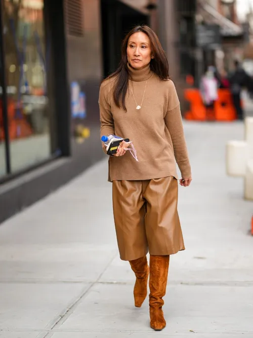 Street Style Look von einem Monochrom-Outfit. Beiger Rollkragen, Leder-Bermuda und Stiefel.