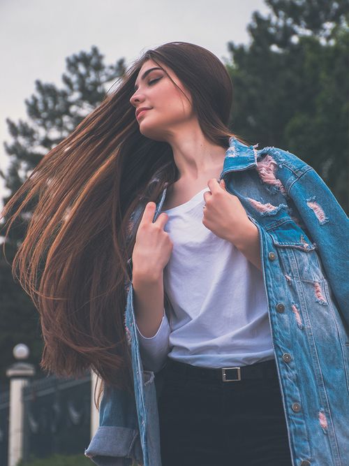 Frau mit sehr langen glatten braunen Haaren und einer Jeansjacke