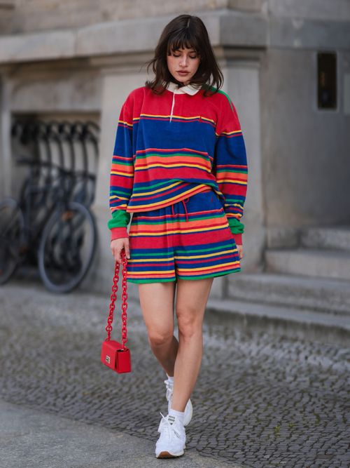 Lea Naumann trägt ein Co-ord von Ralph Polo Lauren mit orangefarbener Tasche und weißen Sneakers in Berlin.