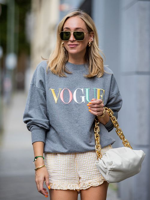 Sonia Lyson in einem grauen Vogue Pullover, einer Shorts und einer Bottega Veneta Tasche.