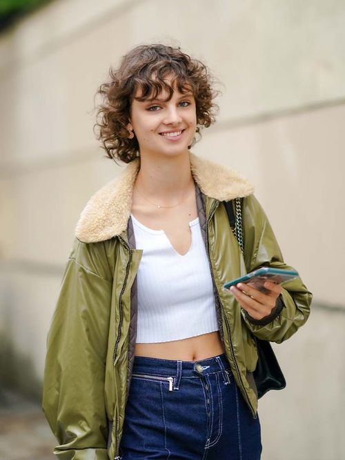 Streetstyle mit einer grünen Jacke, Jeans und einem weißen Top.