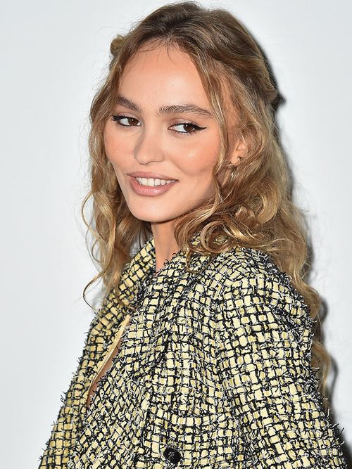 Lily Rose Depp mit gelockten Haaren und einer Tweedjacke