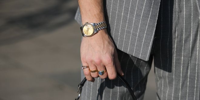 Close-up von Männerhand mit einer Rolex und einer Dior Tasche.