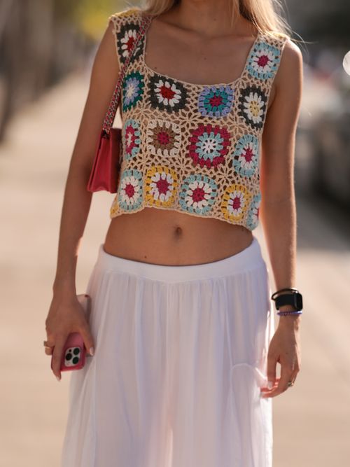 Street Style Look von der Miami Art. Eine Frau trägt ein buntes Häkel-Top mit weißer Hose und roter Tasche.
