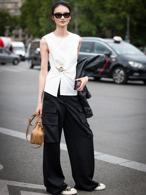 A model wears a white top, black cargo pants and tan bag, outside Chanel, during the Haute Couture Fall/Winter 2023/2024 as part of Paris Fashion Week on July 04, 2023 in Paris, France.