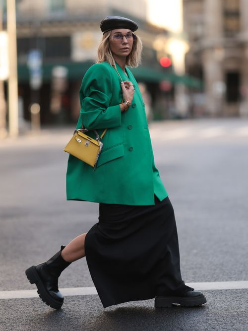 Influencer Karin Teigl trägt eine Oversized Jacke in Grün, mit einem schwarzen Rock, Chelsea Boots und einer gelben Tasche in Paris
