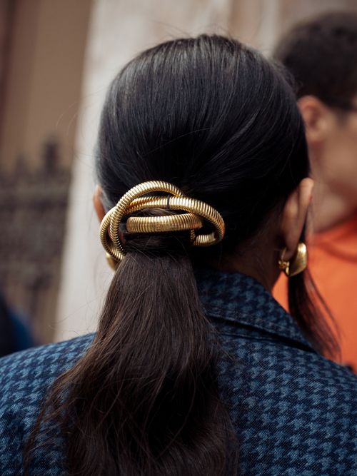 A guest wears a blue jacket and metal hair accessory outside Colours of Benetton during the Milan Fashion Week - Womenswear Spring/Summer 2024 on September 21, 2023 in Milan, Italy.