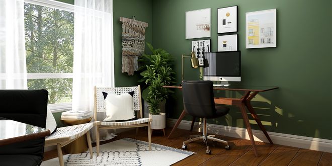 Homeoffice vor einer grünen Wand mit mehreren Bildern und einen Wandteppich.