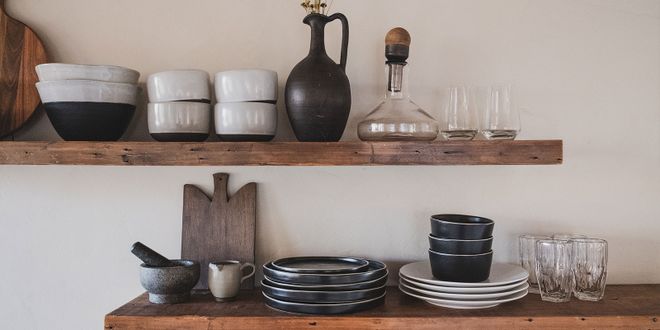 Wandregale aus Holz mit schwarzen und weißem Geschirr, einem Mörser und einigen Gläsern.
