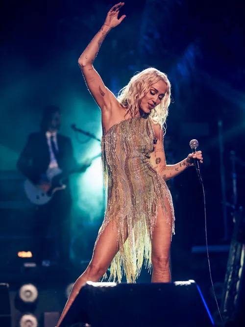 Miley Cyrus performs wearing a shimmery gold mini dress.