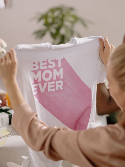 Frau hält T-Shirt in die Luft auf dem Best Mom Ever steht.