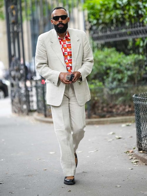 Influencer Jean-Claude trägt einen beigen Hosenanzug, mit buntem Hemd auf der Paris Fashion Week.