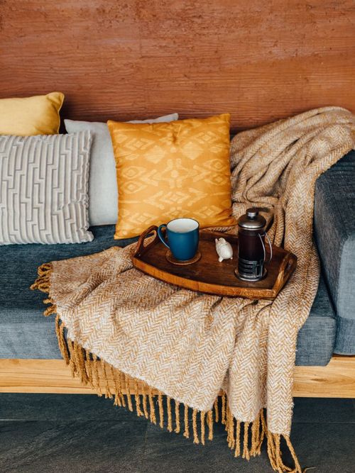 Ein herbstlich dekoriertes Sofa mit Kissen, Decke und einem Teeservice