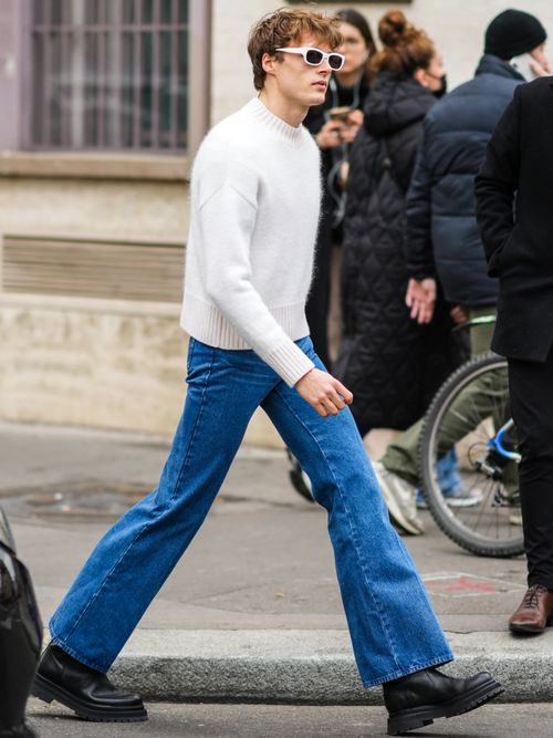 Street Style Look auf der Paris Fashion Week von einem Mann der einen weißen Pulli mit einer flared Jeans trägt