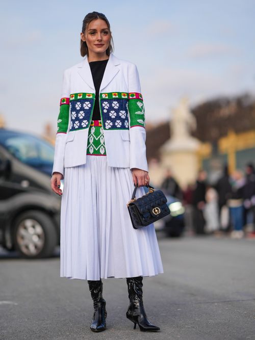 Olivia Palermo trägt eine weiße Jacke mit Aztekenmuster, weißen Rock und Lederstiefel auf der Paris Fashion Week.