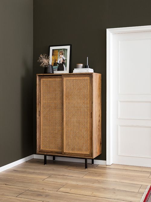 Kommode mit wiener Geflecht vor einer grünen Wand.