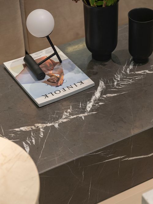 Close-up von einem Sofatisch aus schwarzen Marmor auf dem ein Magazin liegt.