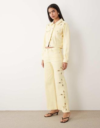 Good American Jeans palazzo a fondo ampio con vita definita e cut-out giallo limone in coordinato
