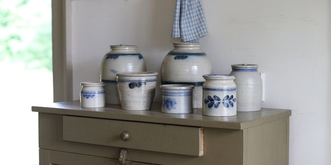 Eine grün gestrichene Komonde auf der verschiedenen Tontöpfe mit blauer Bauernmalerei stehen.