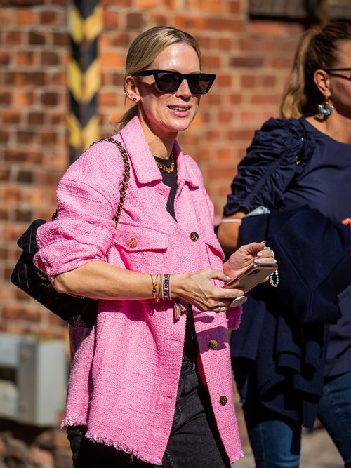 Streetstyle mit einer pinken Boucléjacke und einer schwarzen Sonnenbrille.