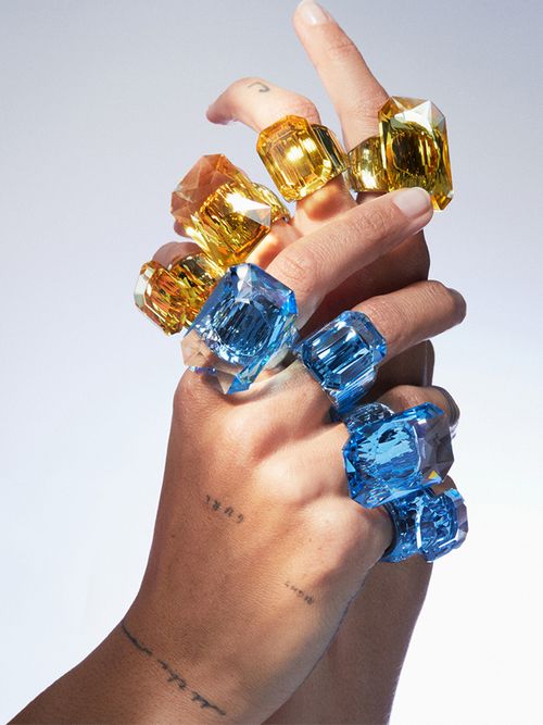 Ineinander verschlungene Hände mit große Kristallringen an jedem Finger.