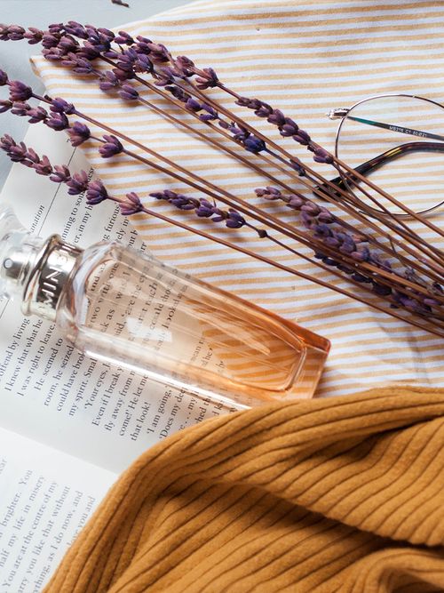 Close up von einem Bündel Lavendel und einer Prafumflasche die auf einem Buch liegen.