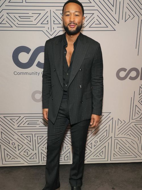 John Legend auf dem Roten Teppich und trägt einen schwarzen Anzug mit schwarzem Hemd.