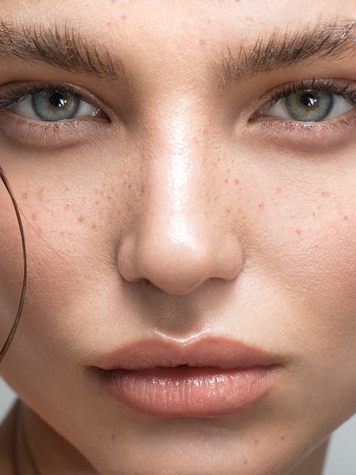 Close up eines Natürlich geschminkten Gesichts mit Sommersprossen und aufgebürsteten Augenbrauen.