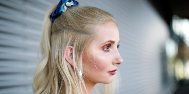 Blonde Frau mit einem einem Half Bun, der von einem blauen Scrunchie gehalten wird.