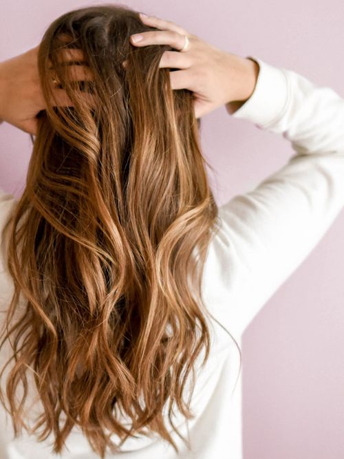 Eine brünette Frau, die sich gerade durch die Haare greift.