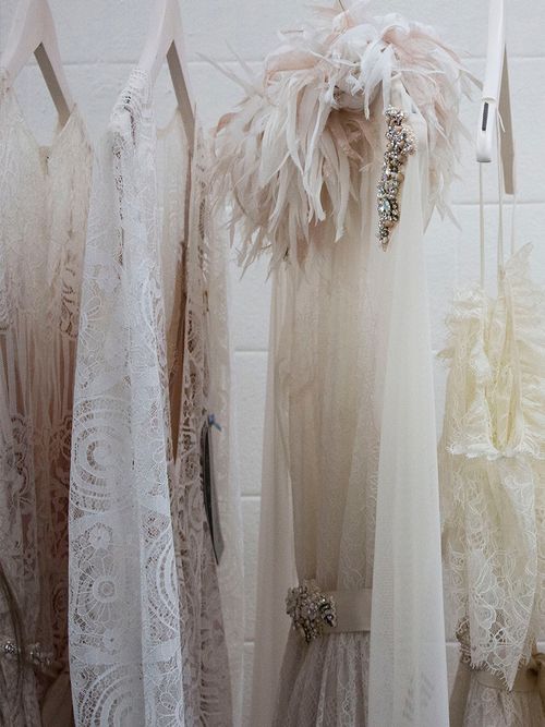 Weiße Brautkleider die nacheinander auf weißen Kleiderbügeln hängen.