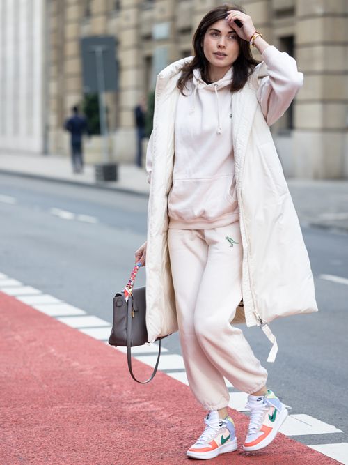 Ira Meindl trägt einen rosaroten Jogginganzug mit weißem Daunengilet und Nike Sneakers in Düsseldorf