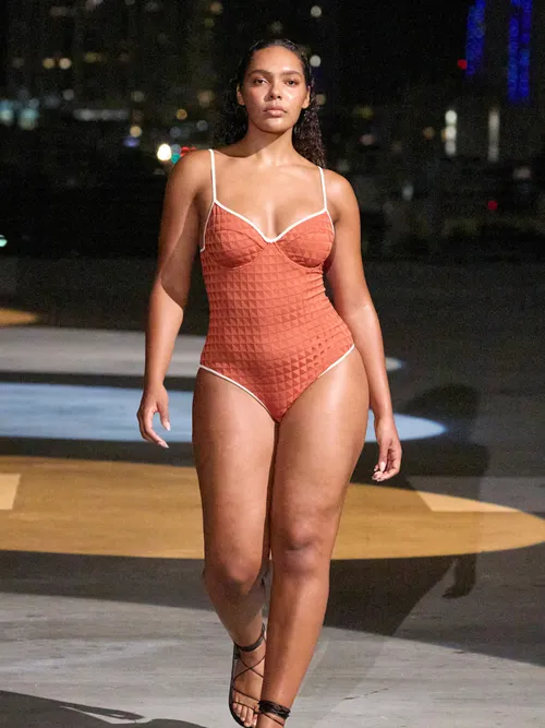 Model wears orange one-piece swimsuit during Miami Fashion Week.