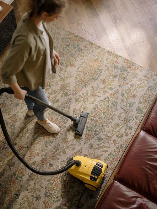 Aus der Vogelperspektive wurde eine Frau beim Staubsaugen fotografiert.