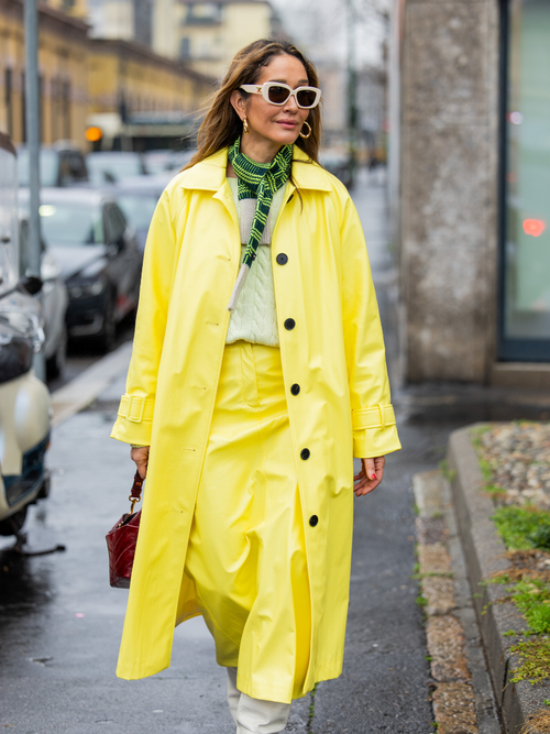 iany Kiriloff wears yellow coat, skirt, brown bag, green scarf, white boots outside Tods during the Milan Fashion Week - Womenswear Fall/Winter 2024-2025 on February 23, 2024 in Milan, Italy.