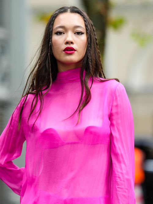Street Style Look von der Paris Fashion Week, wo ein Gast eine pinkes Outfit mit einer Flechtfrisur trägt.