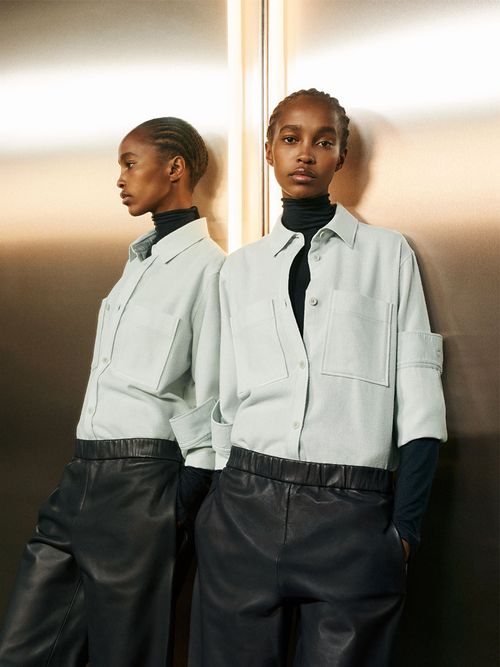 Model mit einer schwarzen Lederculotte und einem weißen Hemd.