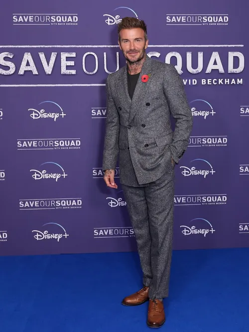 David Beckham auf einer Filmpremiere und trägt einen grau melierten Anzug mit schwarzem T-Shirt.