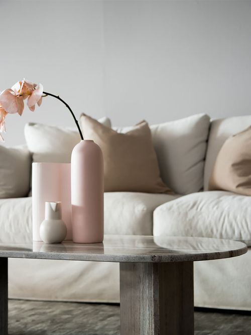 Weißes Sofa mit einem Steintisch vor einer grauen Wand.