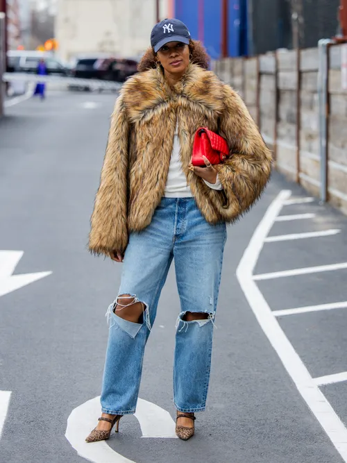 A guest wears a fur jacket, jeans, and NY Yankees baseball cap
