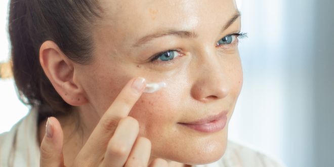 Eine Frau trägt gerade eine Creme um die Augenpartie auf.