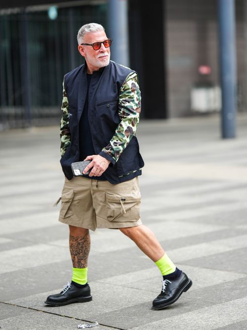 Nick Wooster trägt eine Bomberjacke mit Cargoshorts und neonfarbene Socken, mit Schnürschuhen auf der Paris Fashion Week.